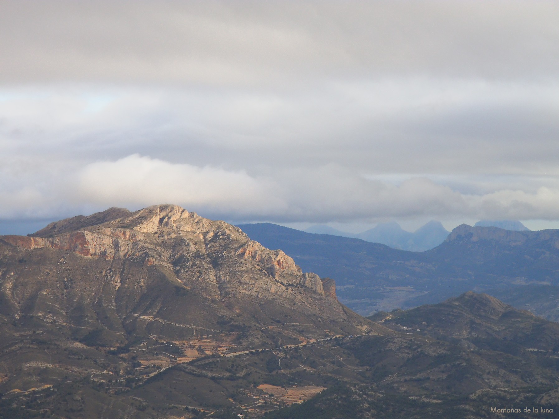 La Penya Migjorn a la izquierda, El Puig Campana nublado, Ponoch, Caval al fondo derecha tapándoles parte de las paredes del Cabeçó d'Or